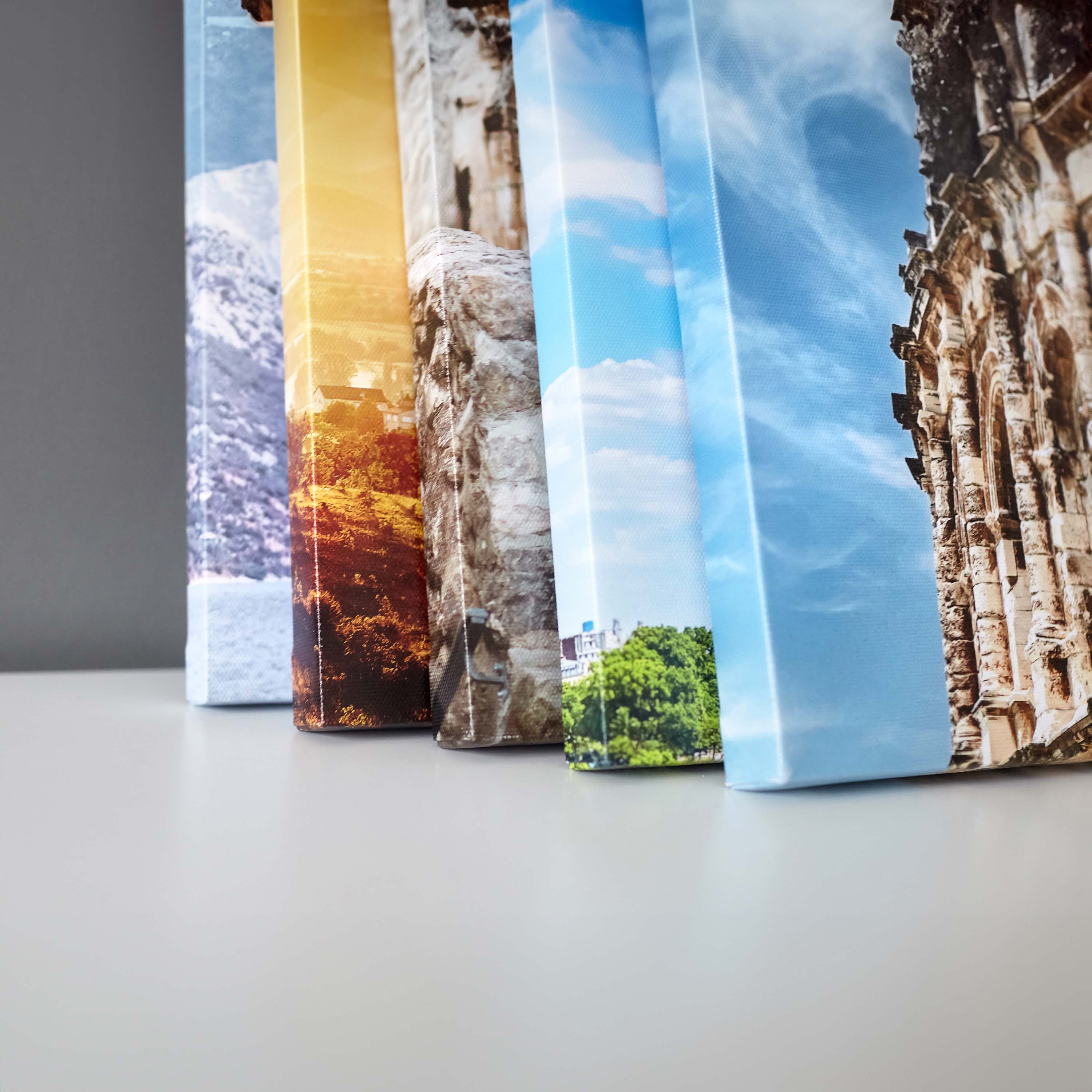 Stack of canvas art prints leaning on wall.