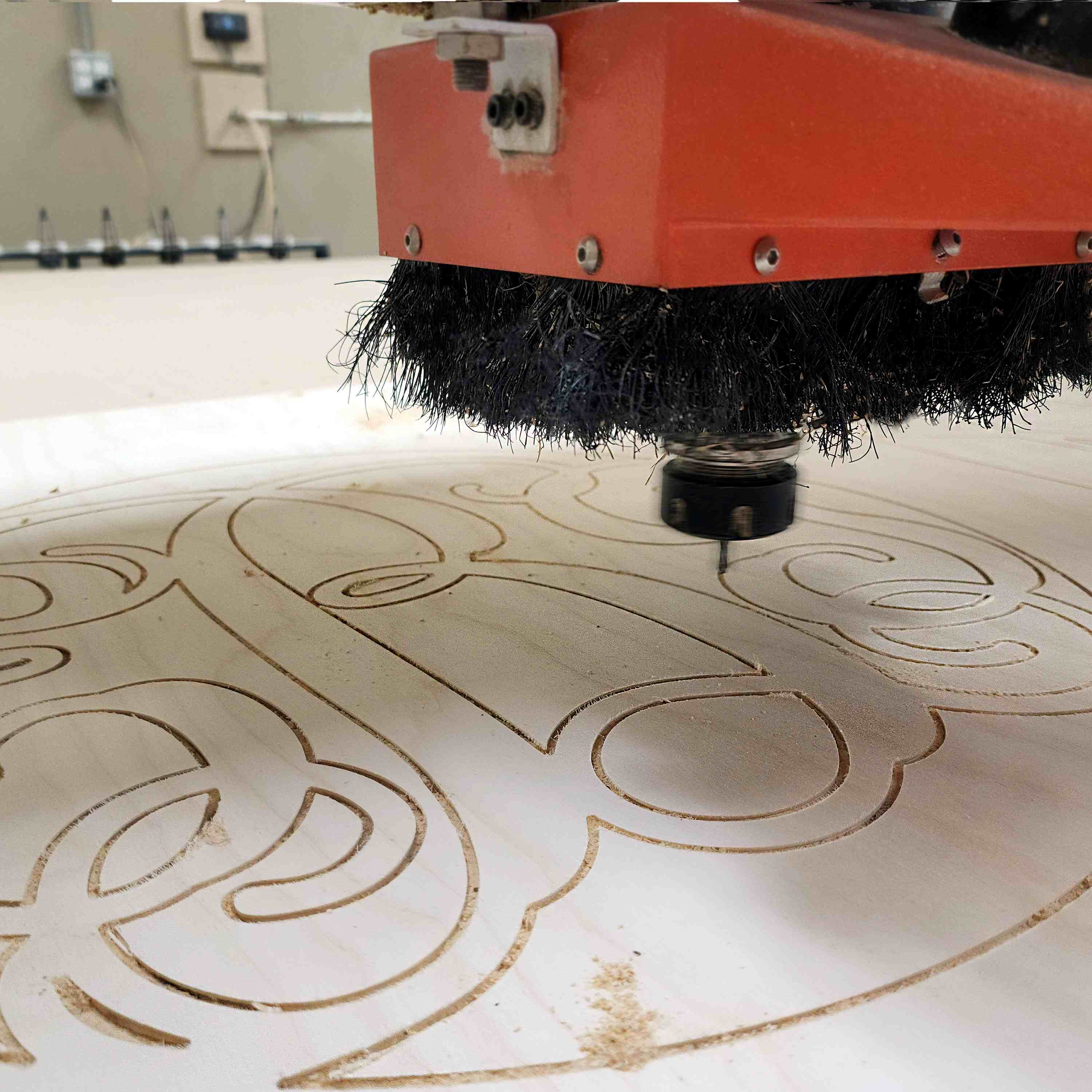 CNC machine cutting a large monogram sign out of wood.
